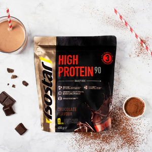 Isostar high protein poeder in de smaak chocolade op een tafel met chocolade eromheen